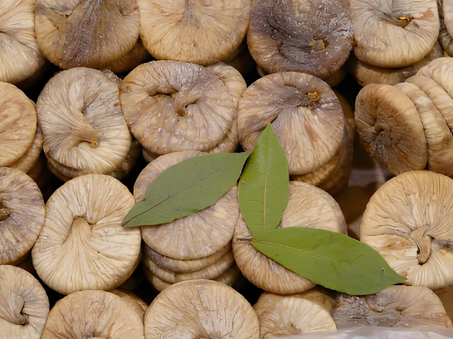 piled dry figs with three leaves on top of them
