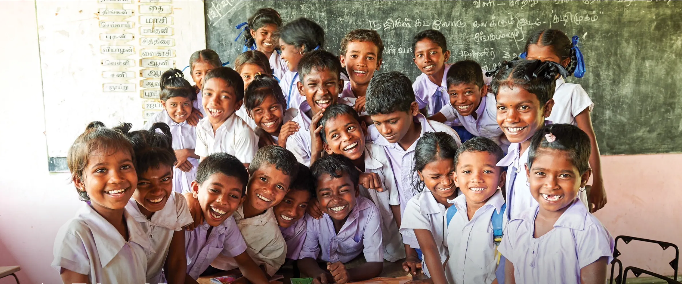 Group of happy kids in a classroom smiling at the camera