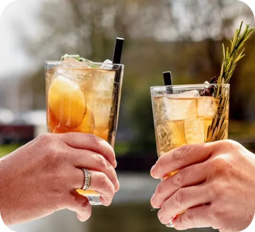 two hands holding a glass of iced tea each and cheering