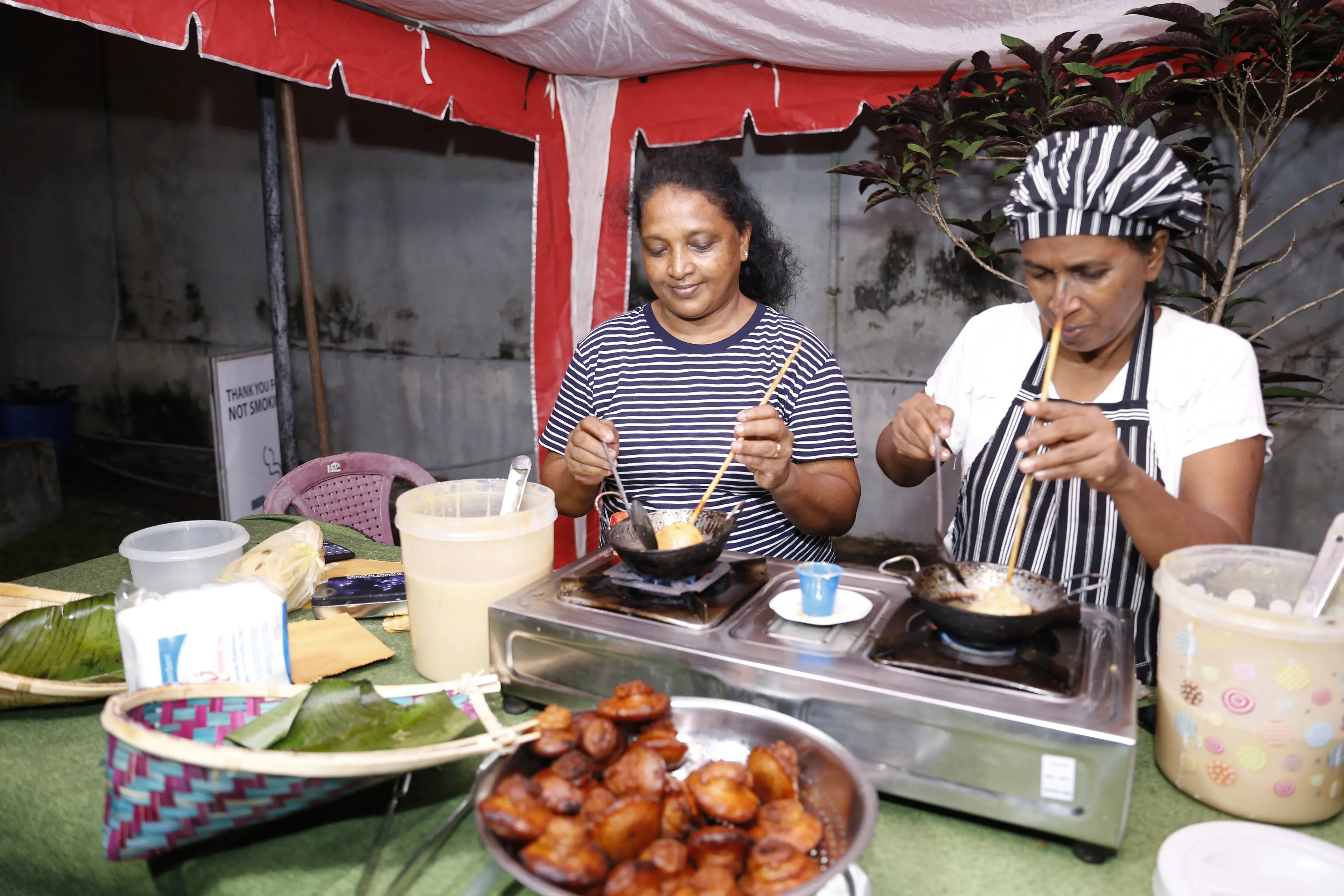 two ladies cooking traditional Sri Lankan food at a stand